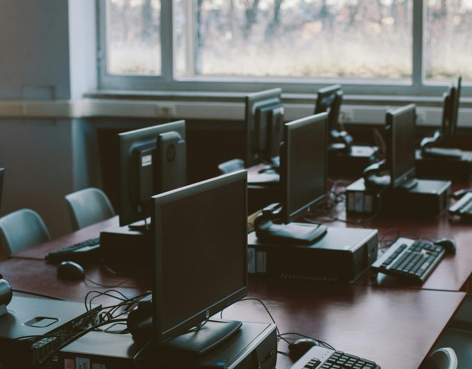 Spacious computer lab with rows of monitors and keyboards in a sunlit room.